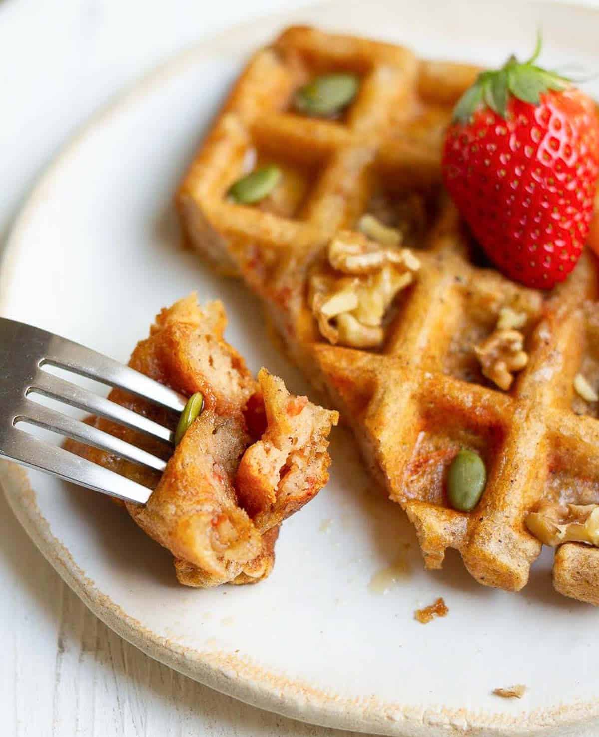 a bite of the waffle on a fork on a plate.