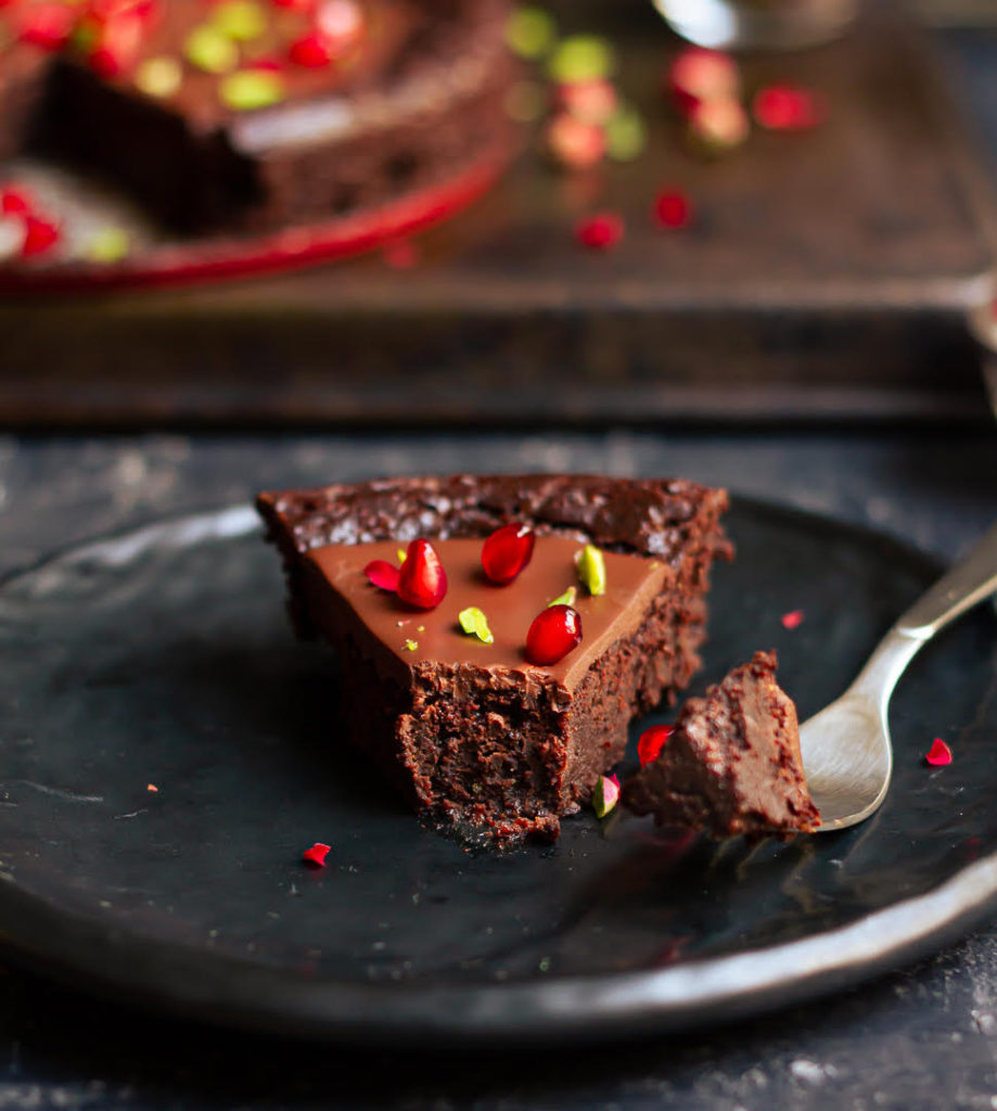 A slice of chocolate cake on a plate with a bite taken out on a fork.