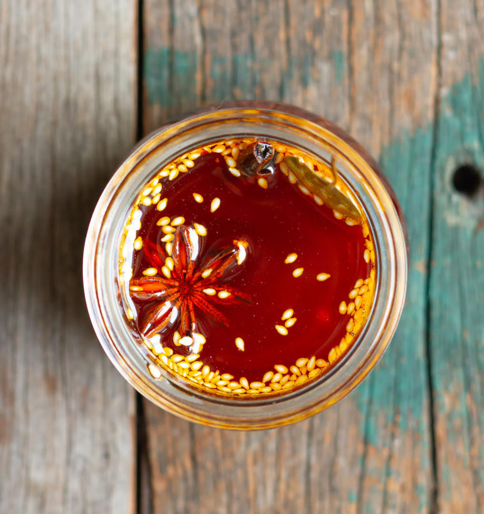 Chinese chili oil in a glass jar on a wooden surface.