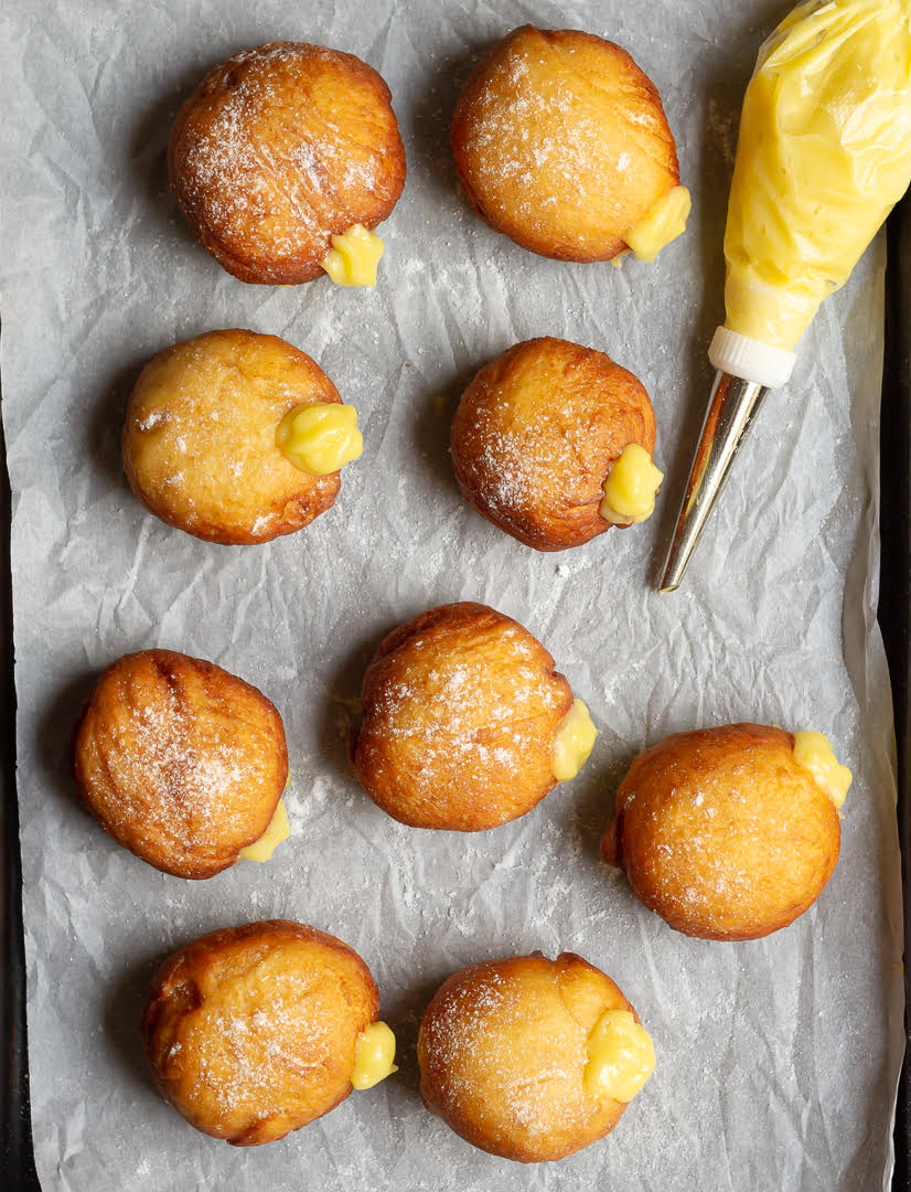 Piping bag and donuts filled with mango curd.