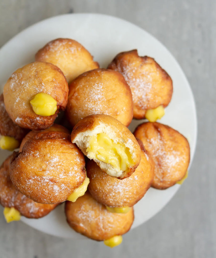 Mango donuts on a plate with one donut half on top to show the filling inside.