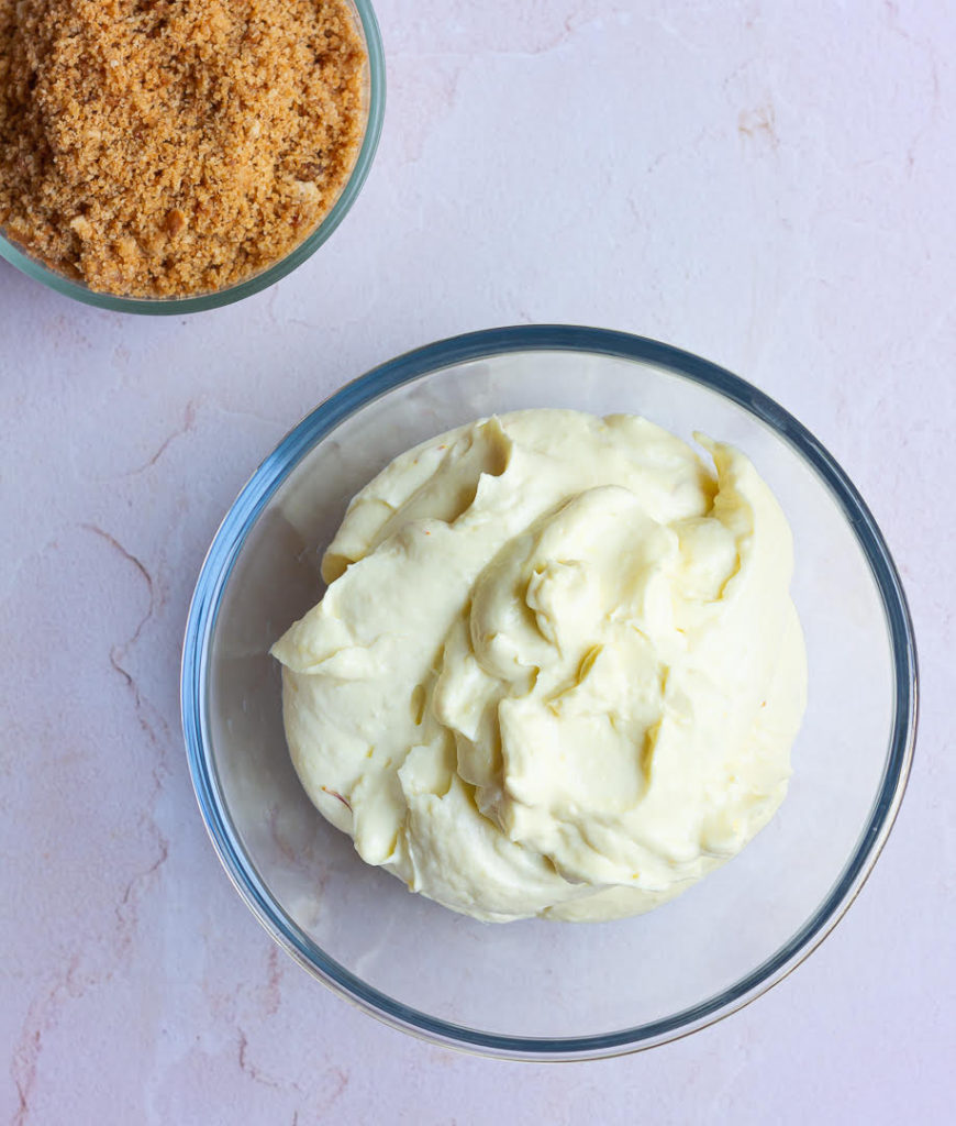 Filling and cookie crust for no-bake mango cheesecake in 2 bowls.