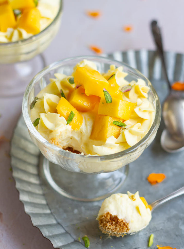 A bowl of mango cheesecake with a spoonful of the cheesecake.