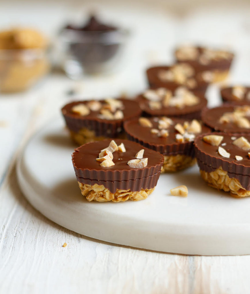 Peanut Butter Chocolate Oat Cups on a white tray with ingredients in the background