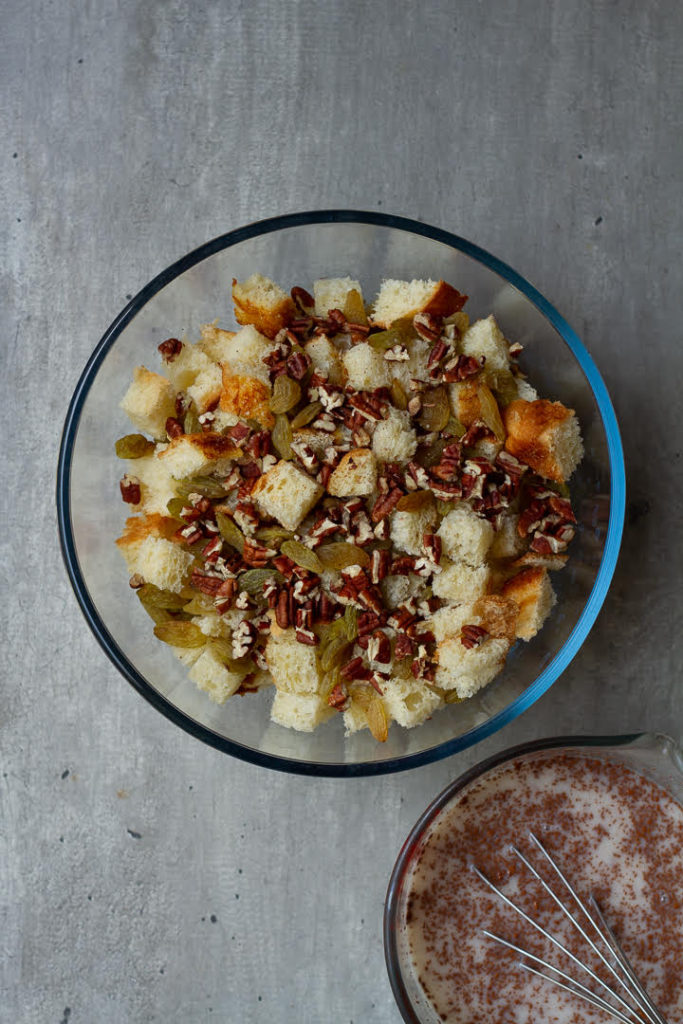 bread cubes with raisins and pecans in a mixing bowl.