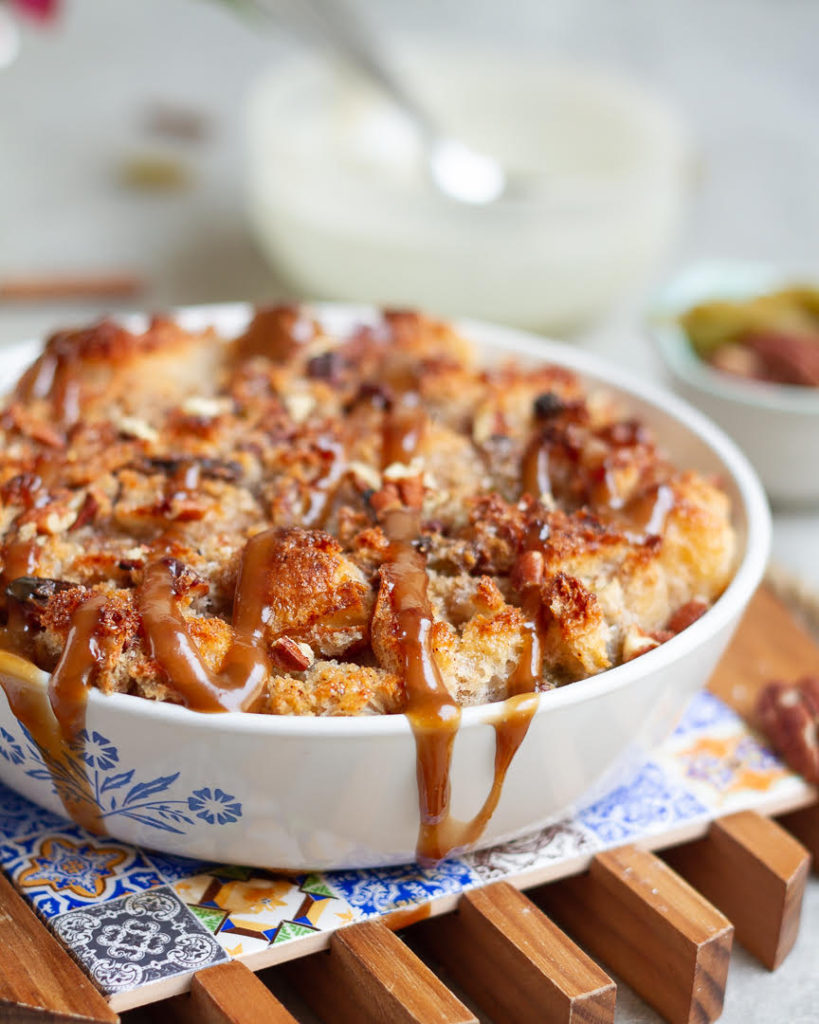 Cinnamon Bread Pudding in a baking dish with caramel drizzled over the top.