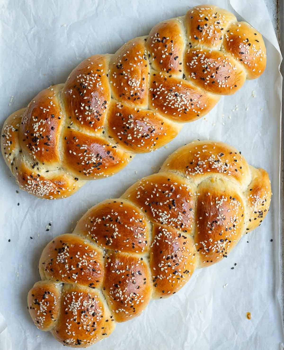 2 baked loaves of braided breads on parchment paper.
