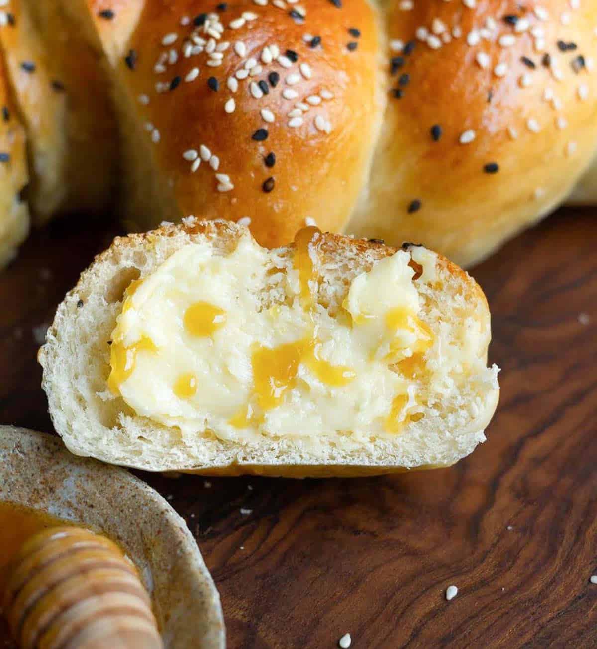 A slice of bread with butter and honey on a wooden surface.