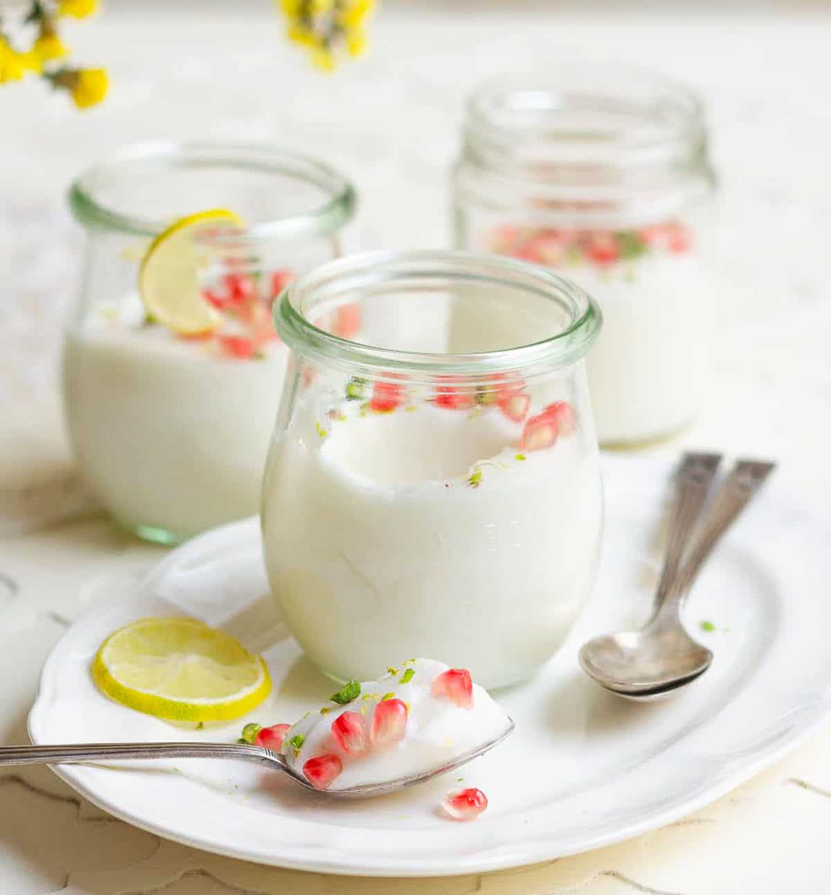 3 jars of panna cotta with one spoonful of panna cotta on a platter.