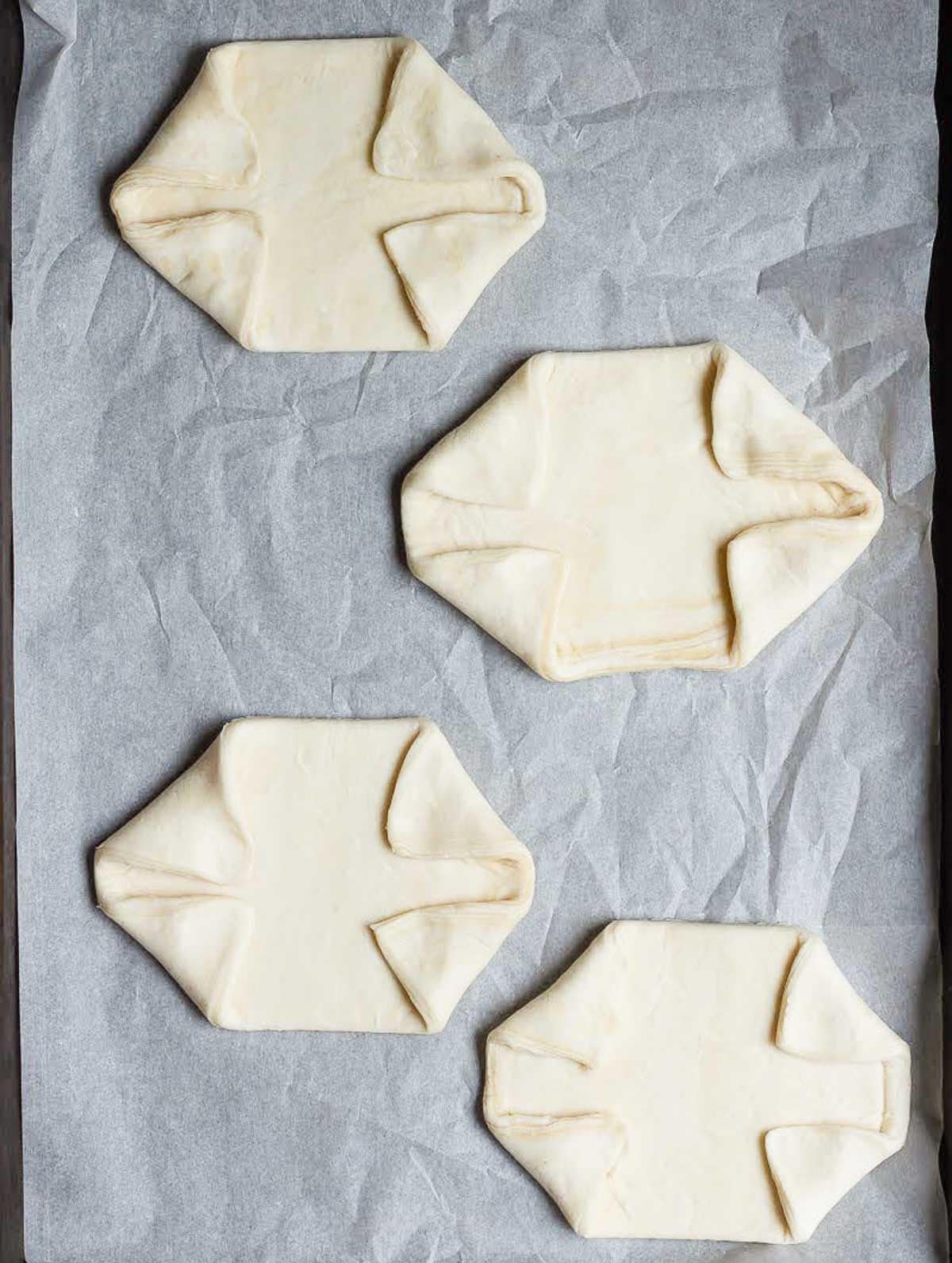 4 pieces of puff pastry on parchment paper with edges folded over.