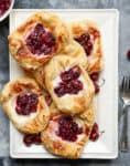Puff pastry tarts with cherries on a platter.