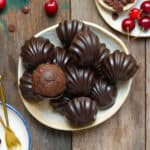 Chocolate cherry madeleines on a plate with ingredients in the background.