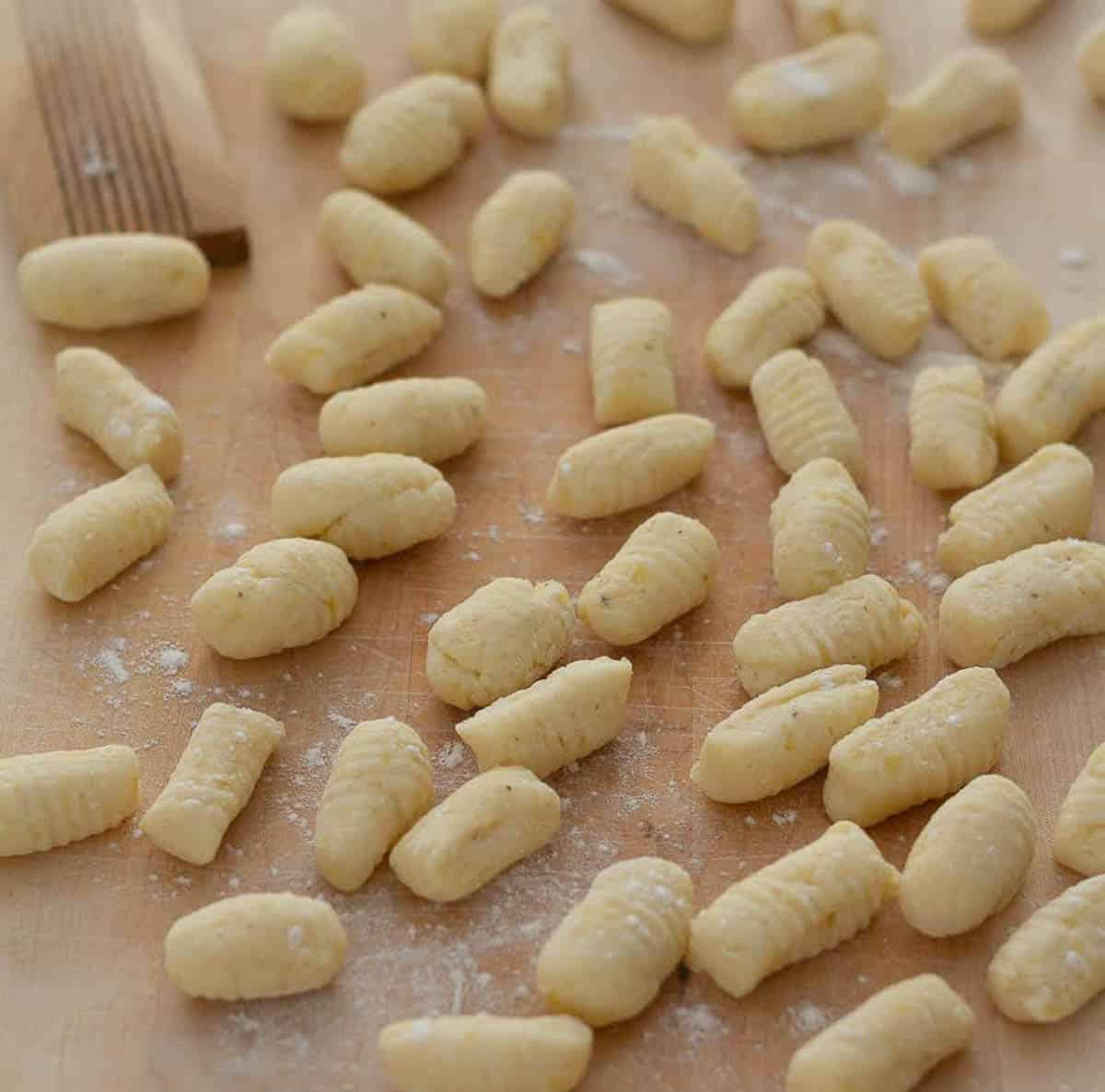 Gnocchi dusted with flour on a wooden board.