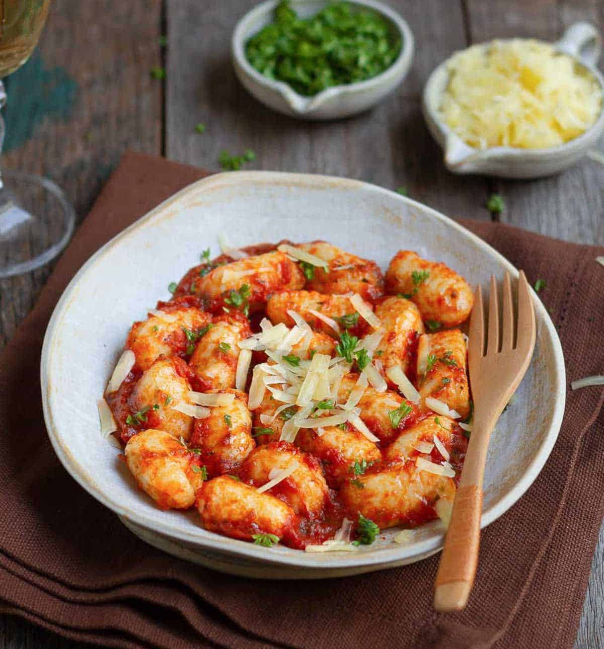 Gnocchi with tomato sauce, cheese, and parsley on a plate with a fork.