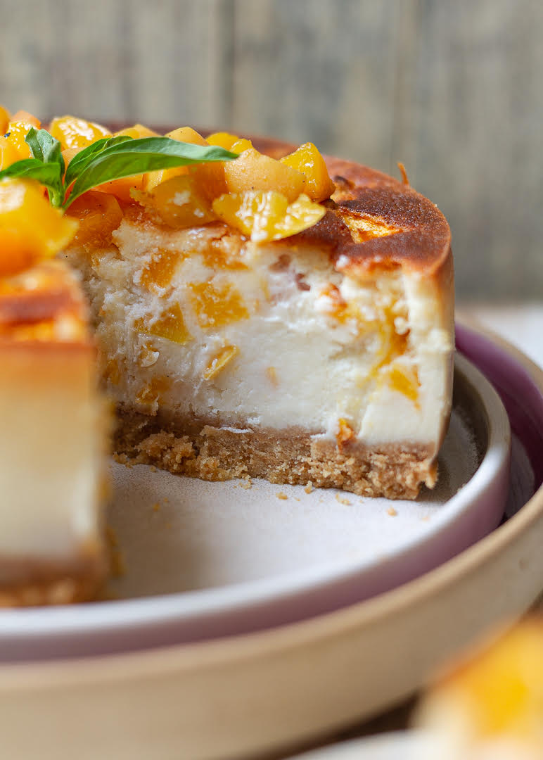 A cheesecake with peaches on a plate.