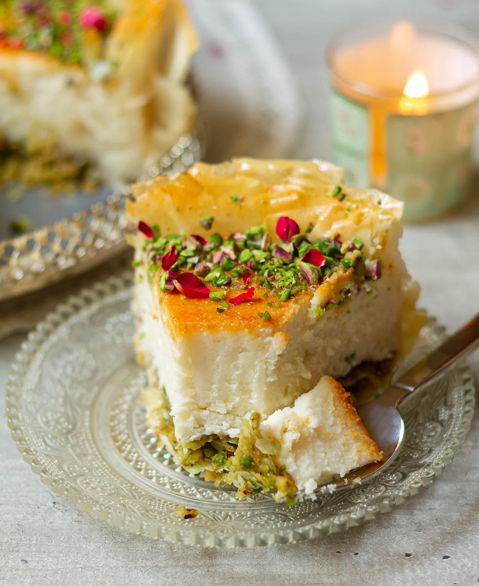A slice of baklava cheesecake with a bite taken with a fork.
