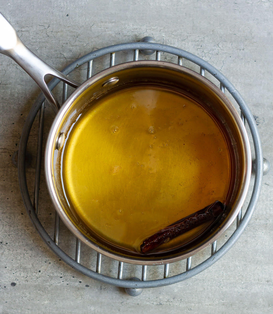 Syrup for baklava cheesecake with cinnamon stick in a small saucepan.