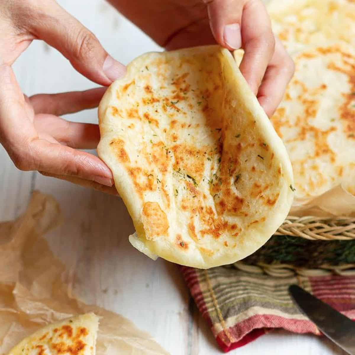 A flatbread half-folded in a hand to show its softness.