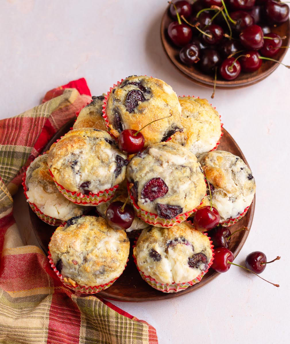 Muffins with cherries on a wooden bowl with a red napkin.