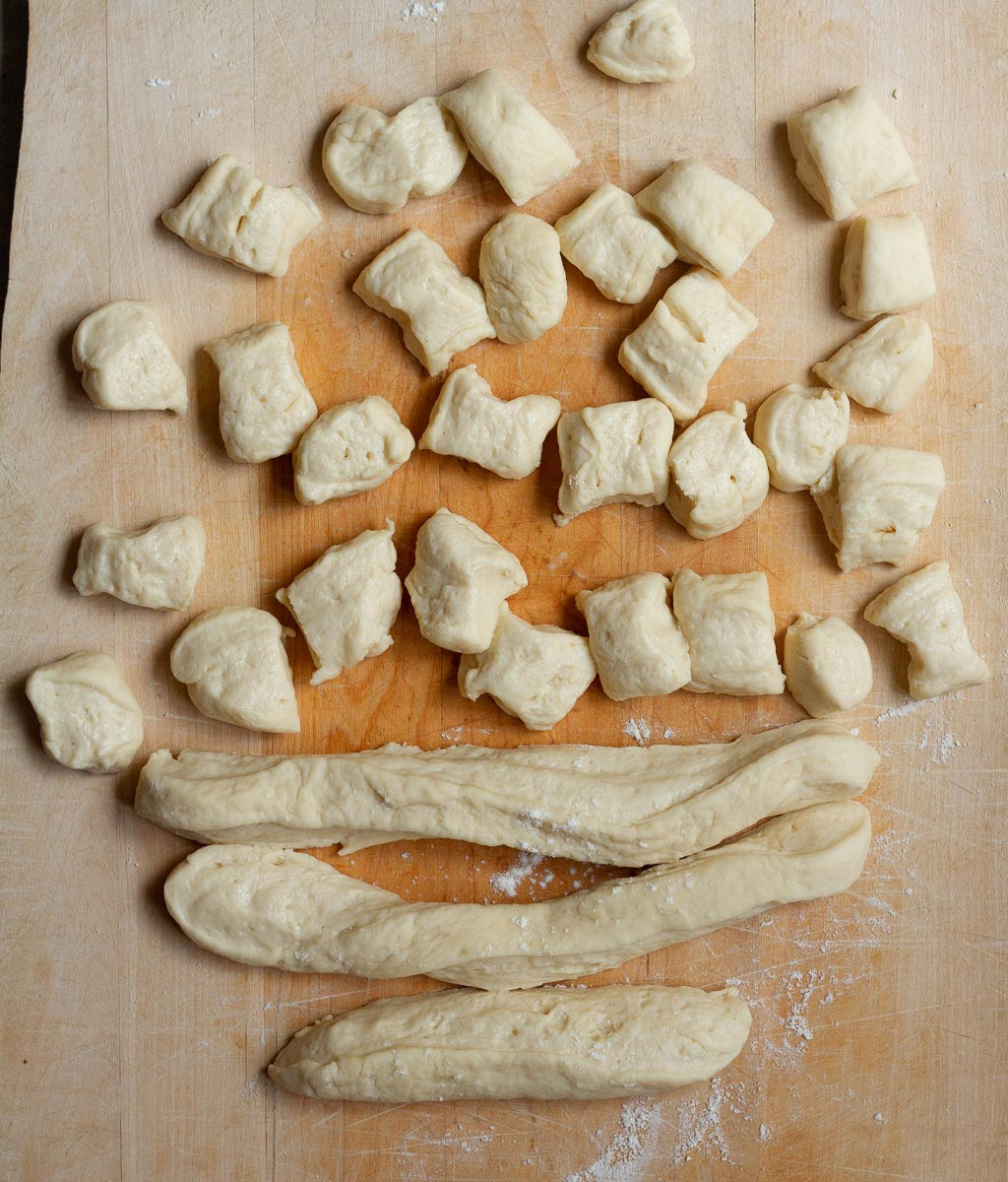 Dough cut into small pieces on a wooden board.