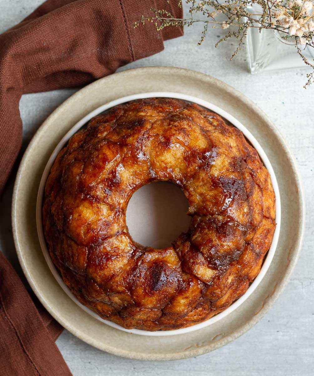 Cinnamon monkey bread on 2 ceramic plate with a brown napkin underneath.