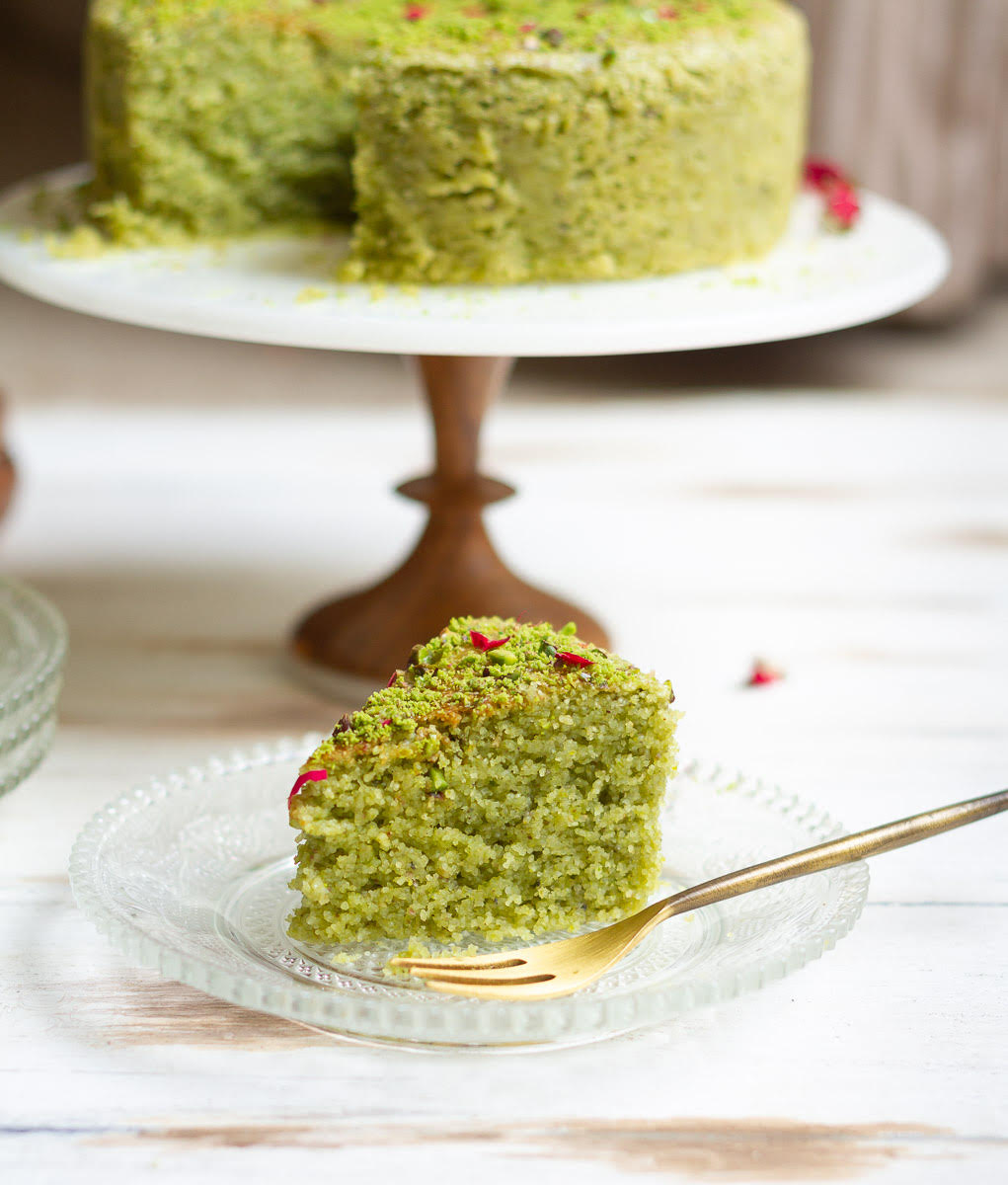 A slice of pistachio cake on a small plate with a fork.