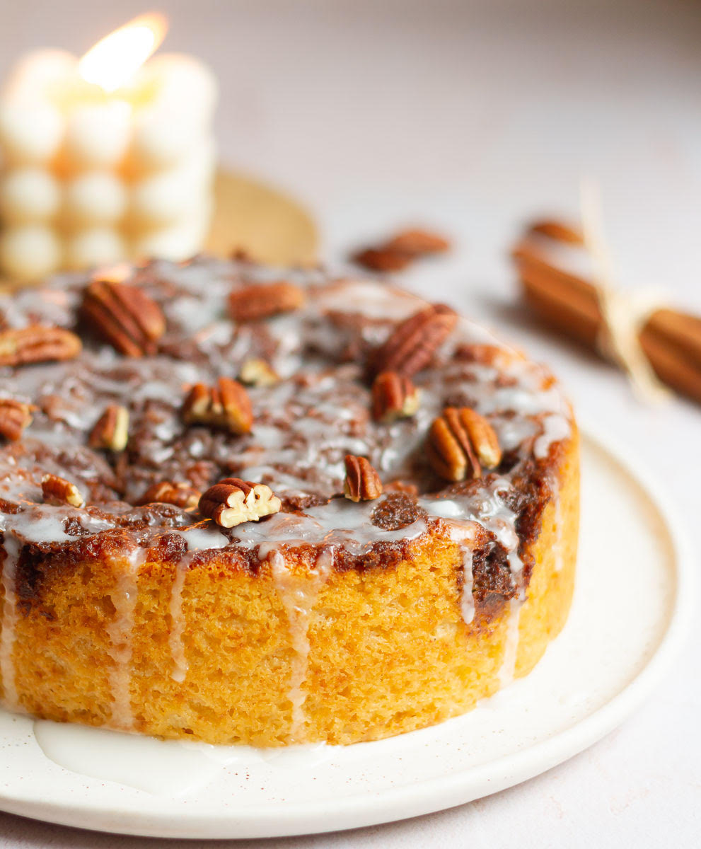Cinnamon cake topped with glaze and pecans on a platter.