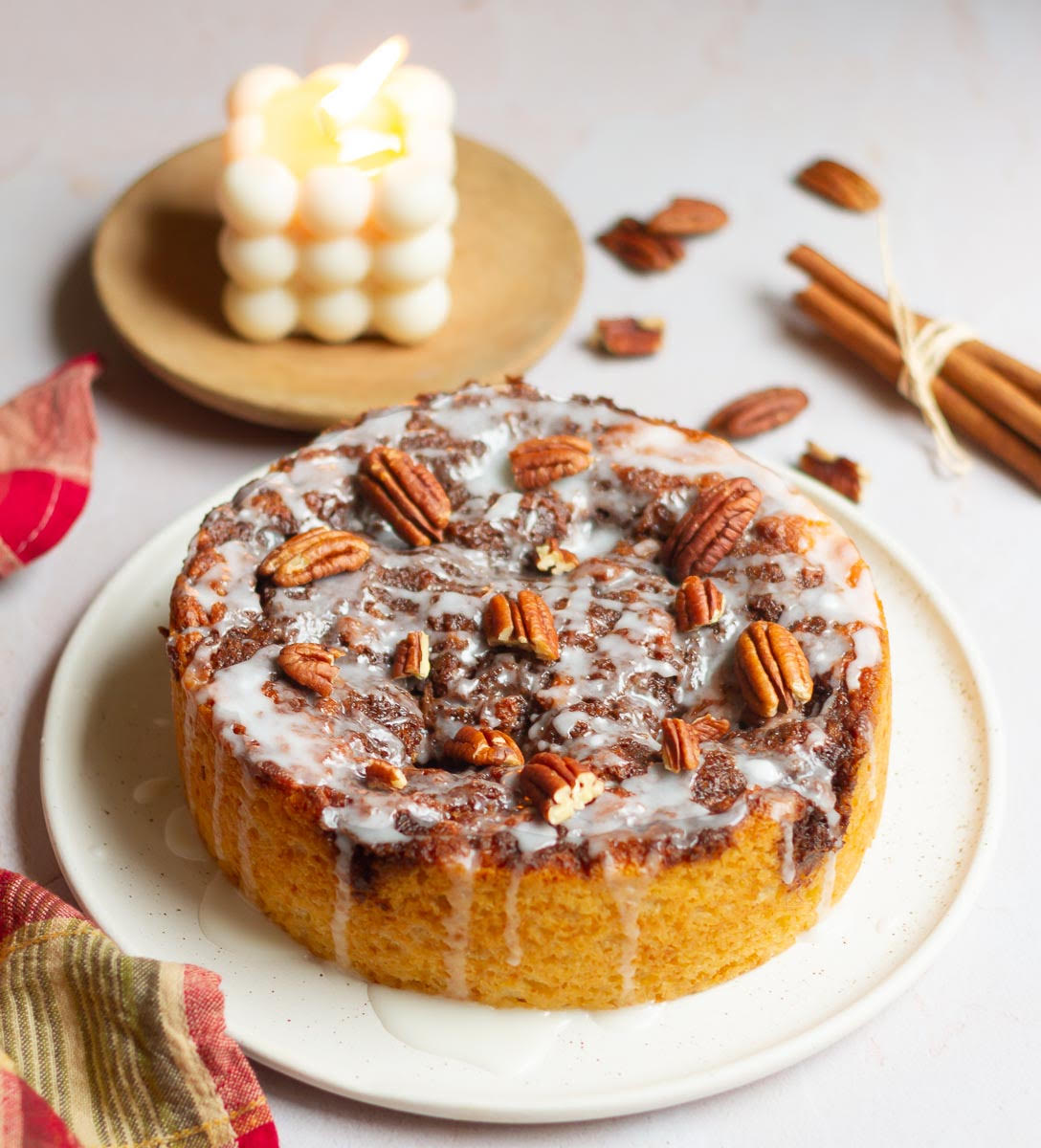 cinnamon cake with glaze and pecans on a platter.