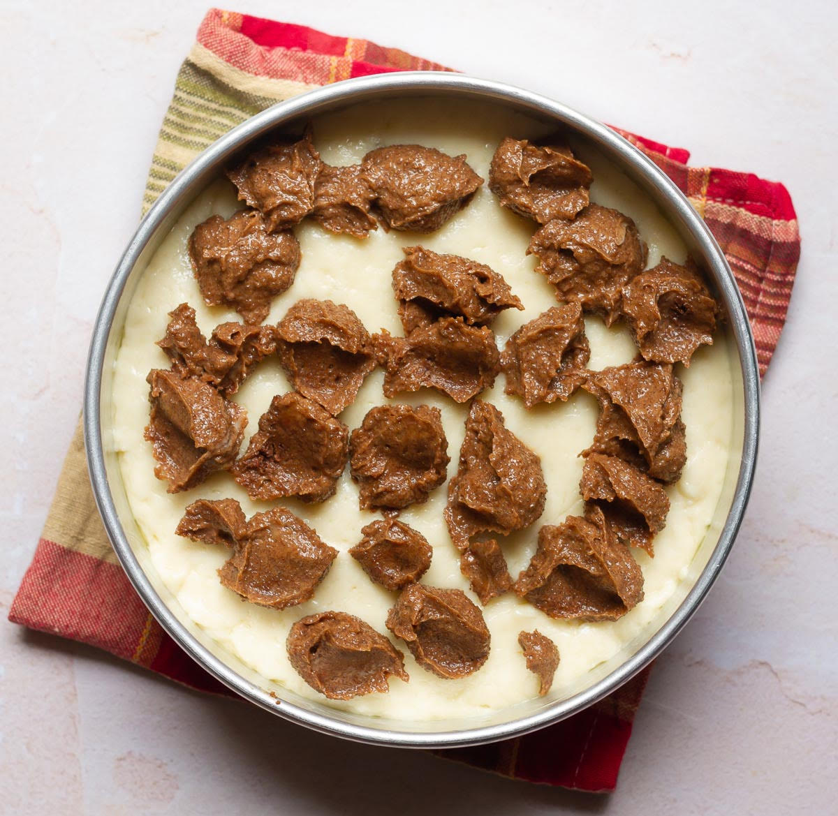 Spoonfuls of cinnamon topping on top of cake batter.