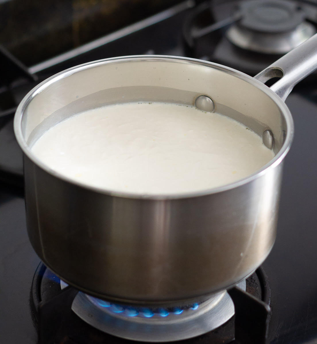 Gently boiling milk, cream and salt in a saucepan on low heat.