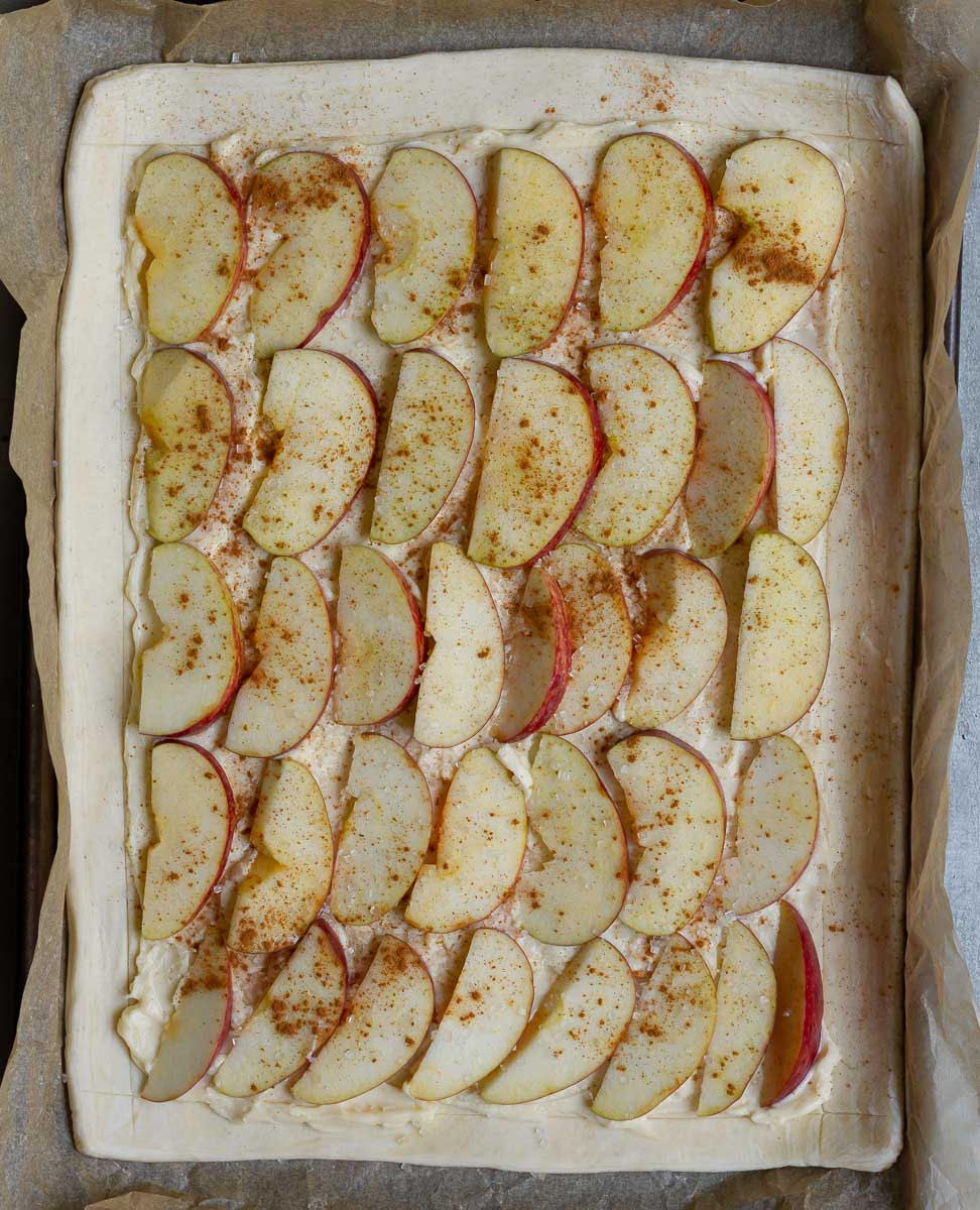 Cream cheese and sliced apples with cinnamon on top of the pastry.
