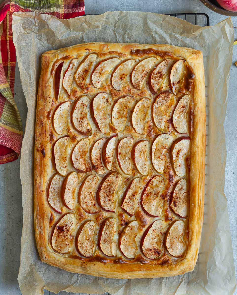 Baked apple puff pastry tart on parchment paper.