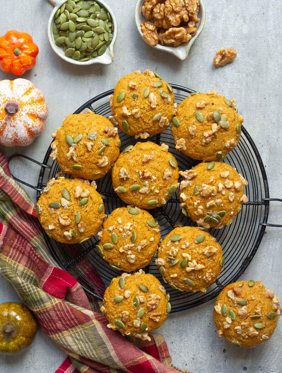 Pumpkin muffins on a wire rack with a napkin and ingredients around.
