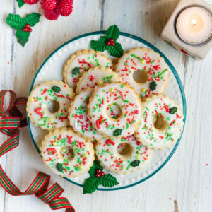 decorated christmas wreath cookies on a plate with christmas decor around.