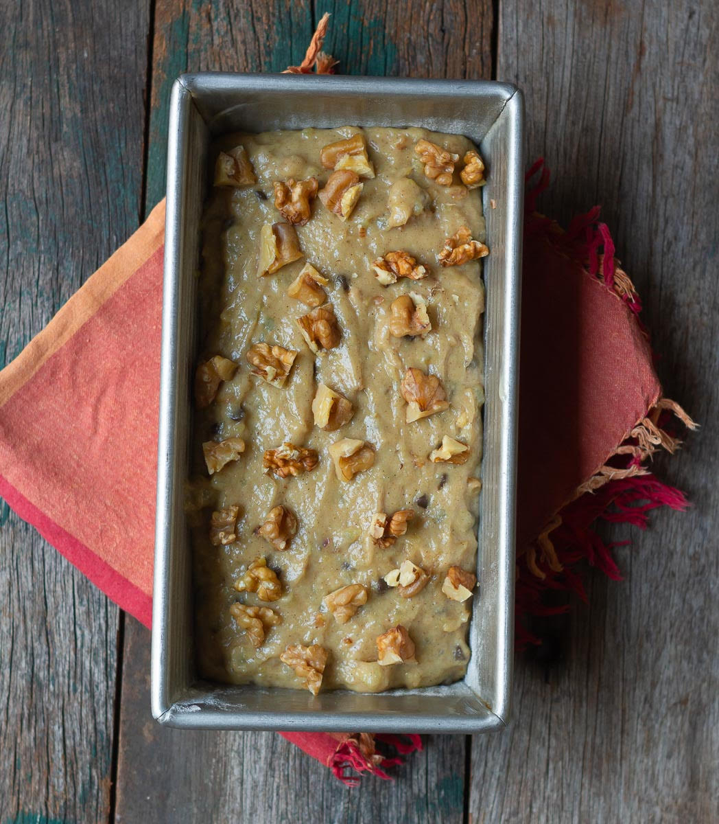 Batter in a loaf pan, topped with walnuts.