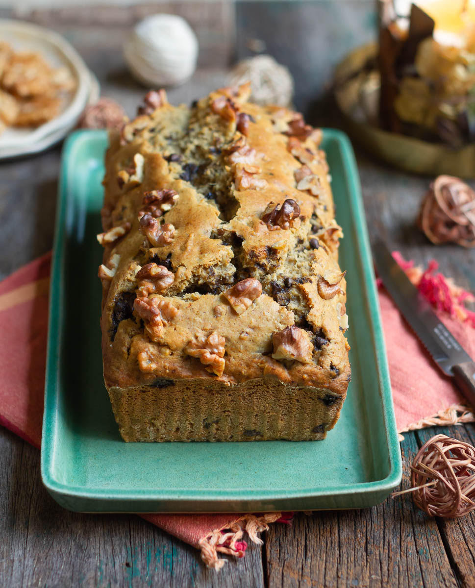 Sweet potato bread on a platter with ingredients in the background.
