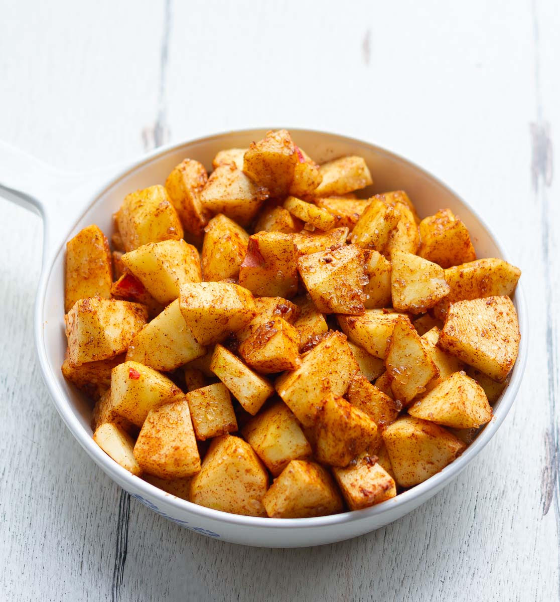 apples mixed with cinnamon powder, lemon juice, and sugar in a baking dish.