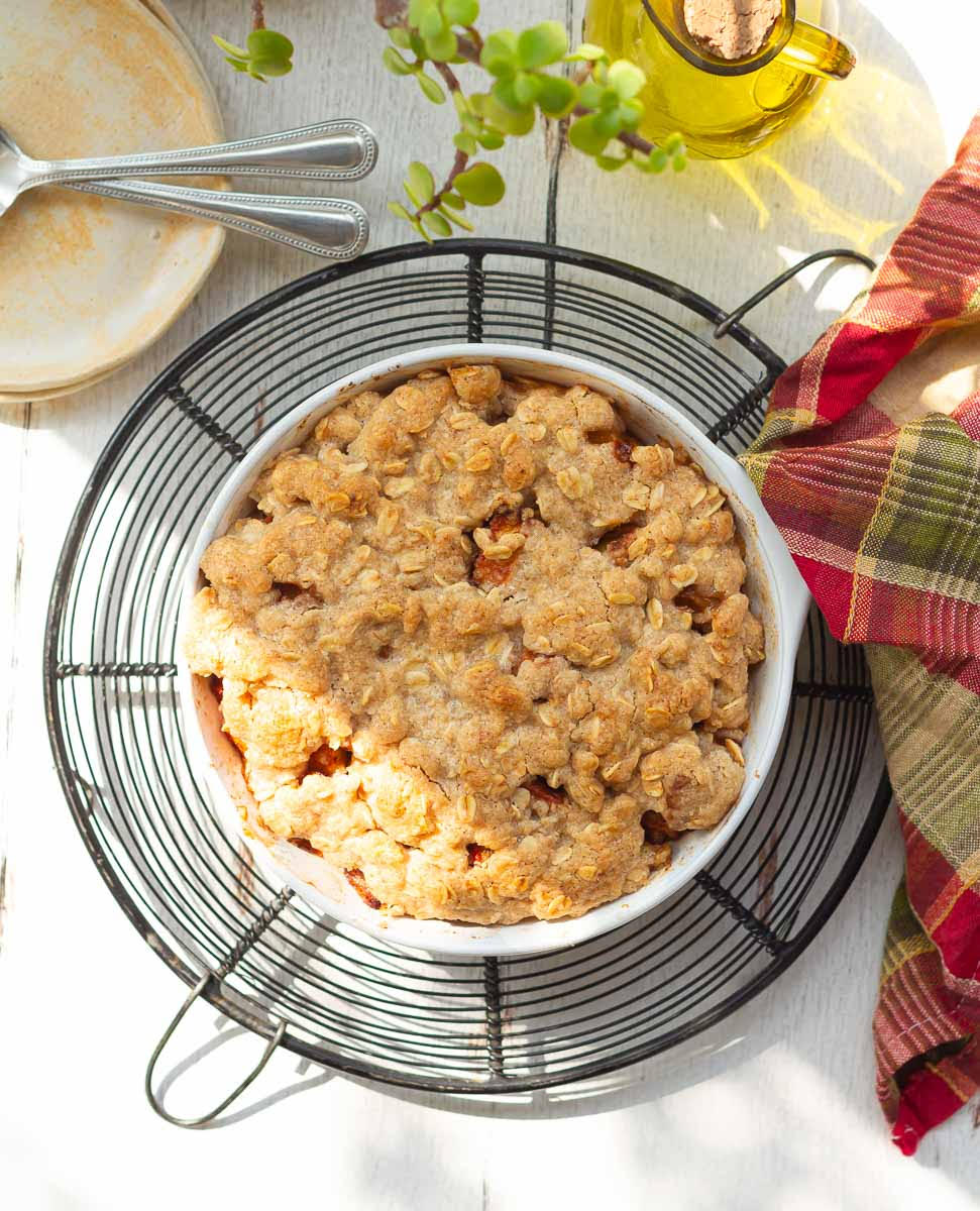 apple crisp in a baking dish on a trivet with a kitchen towel.