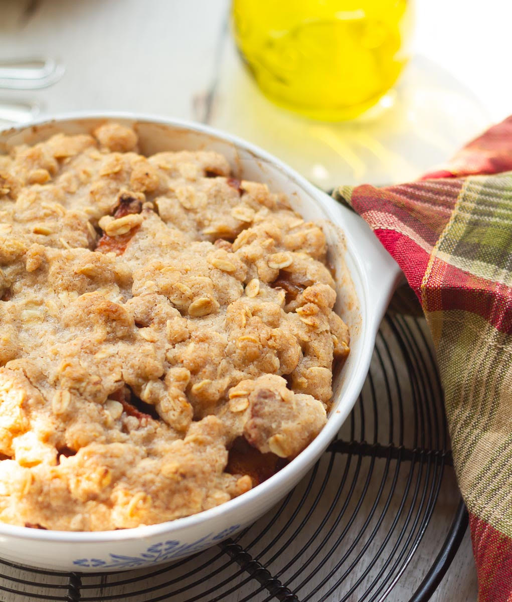 baked apple crisp in a baking dish on a trivet with a kitchen towel.