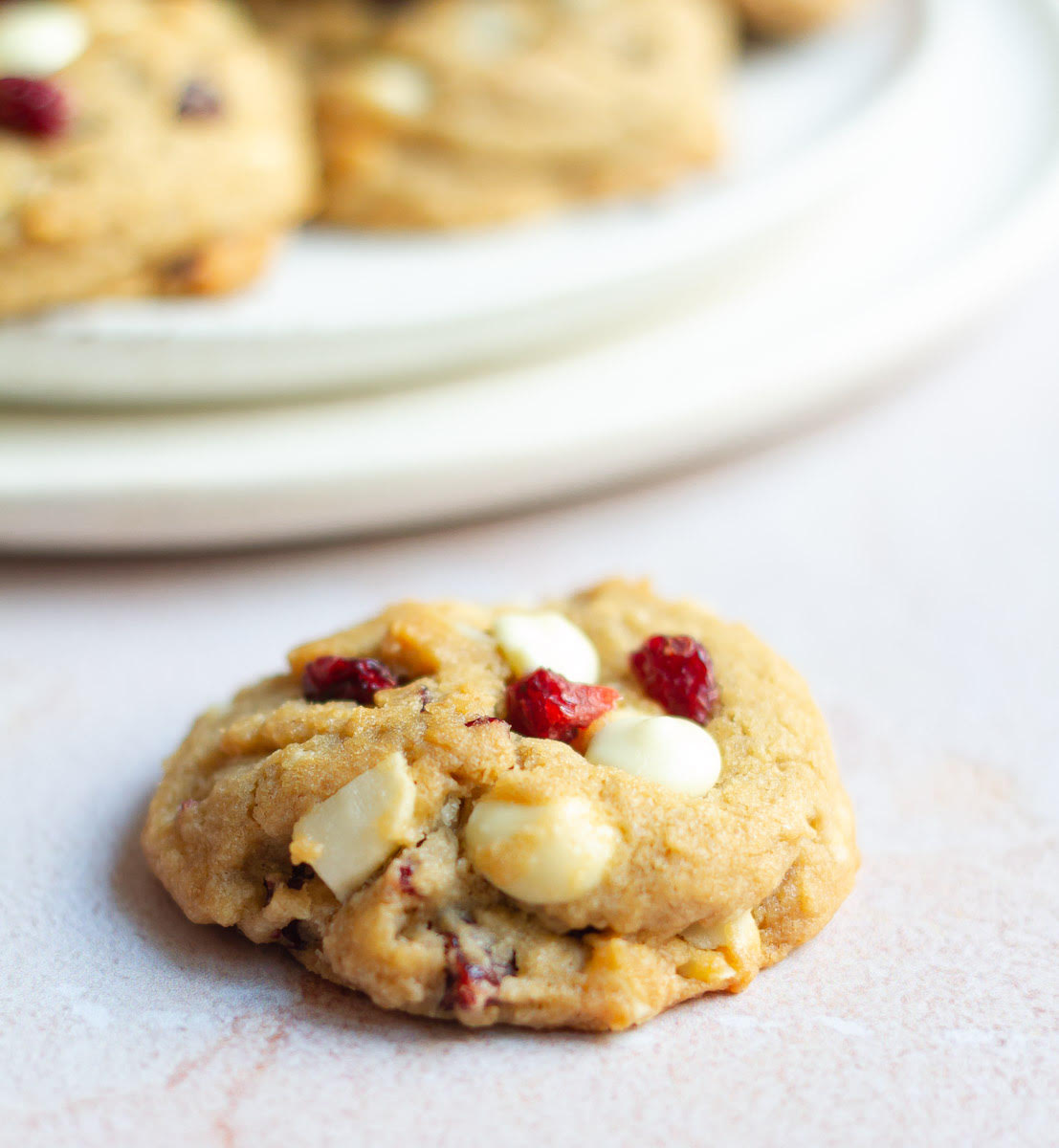 a cookie with white chocolate and cranberries on a surface.