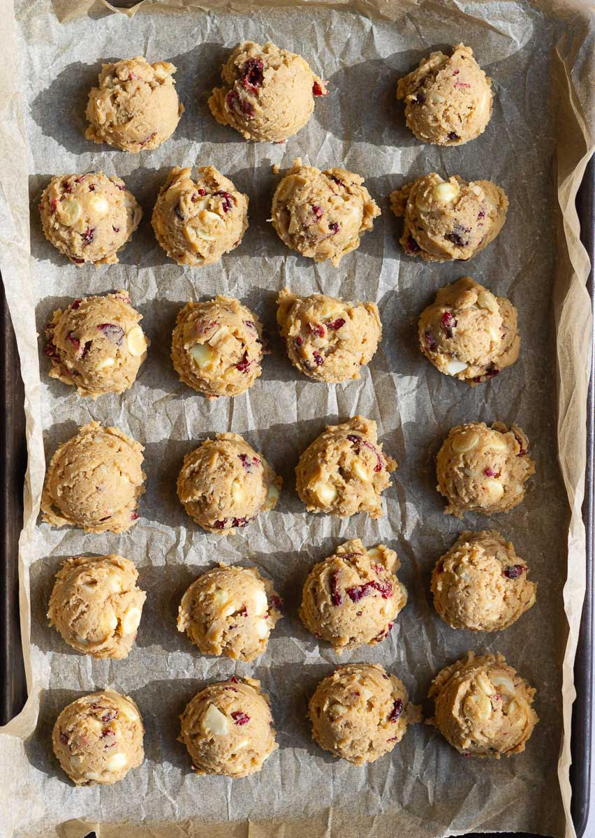 Scooped out cookie dough on parchment paper.