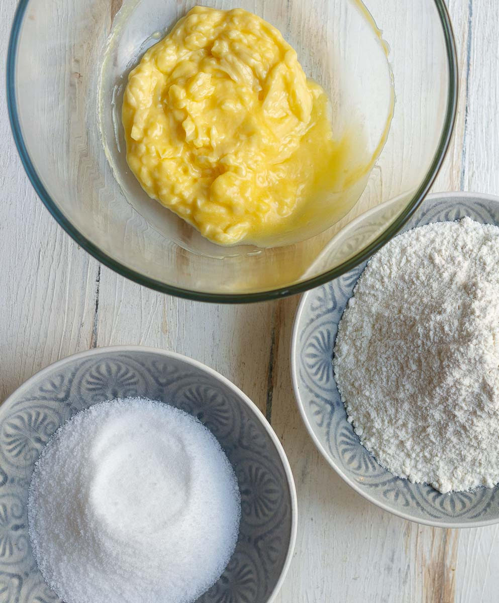 Butter, flour, and sugar in different bowls.