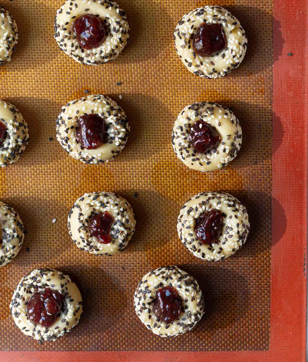 Cookie balls coated with sesame seeds filled with jam in the center.