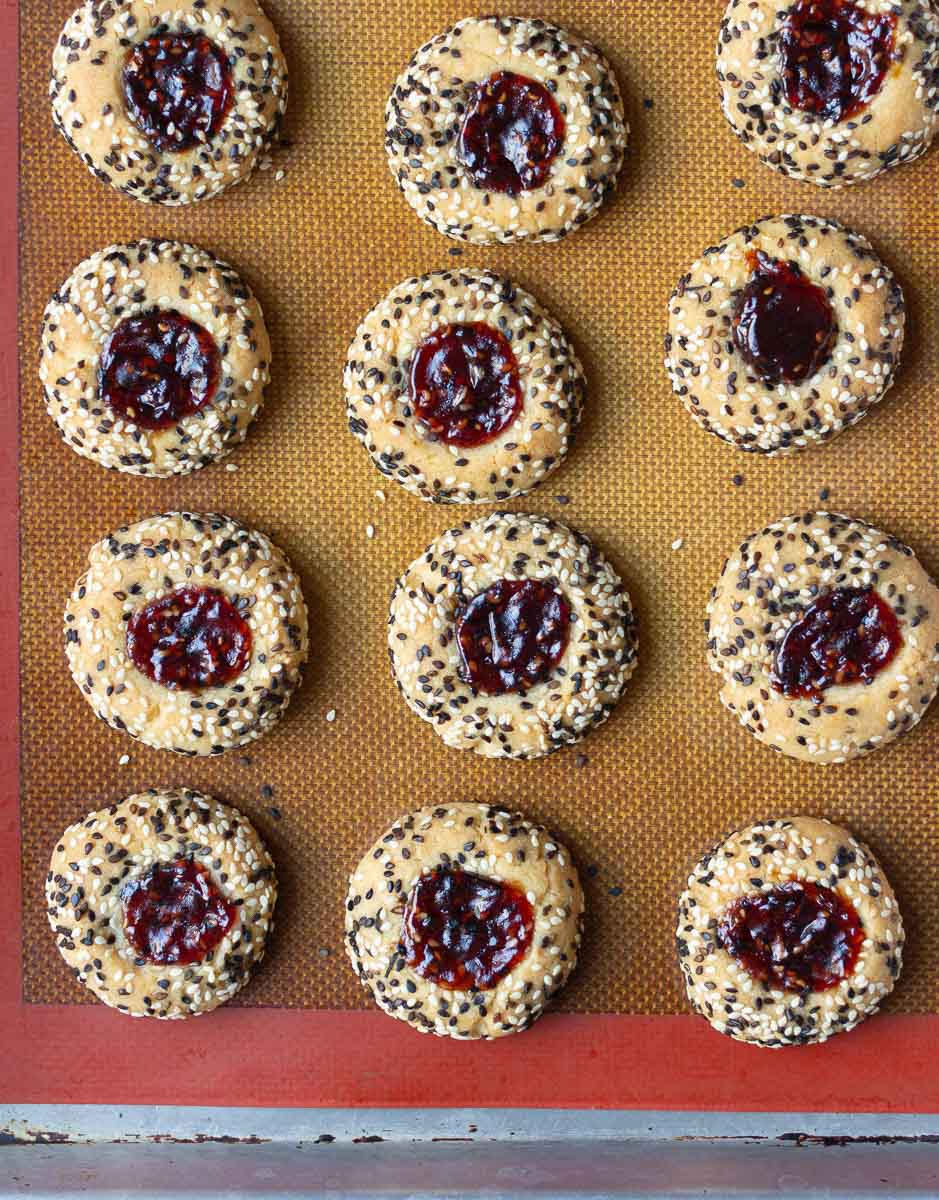 Baked jam thumbprint cookies on a baking tray.