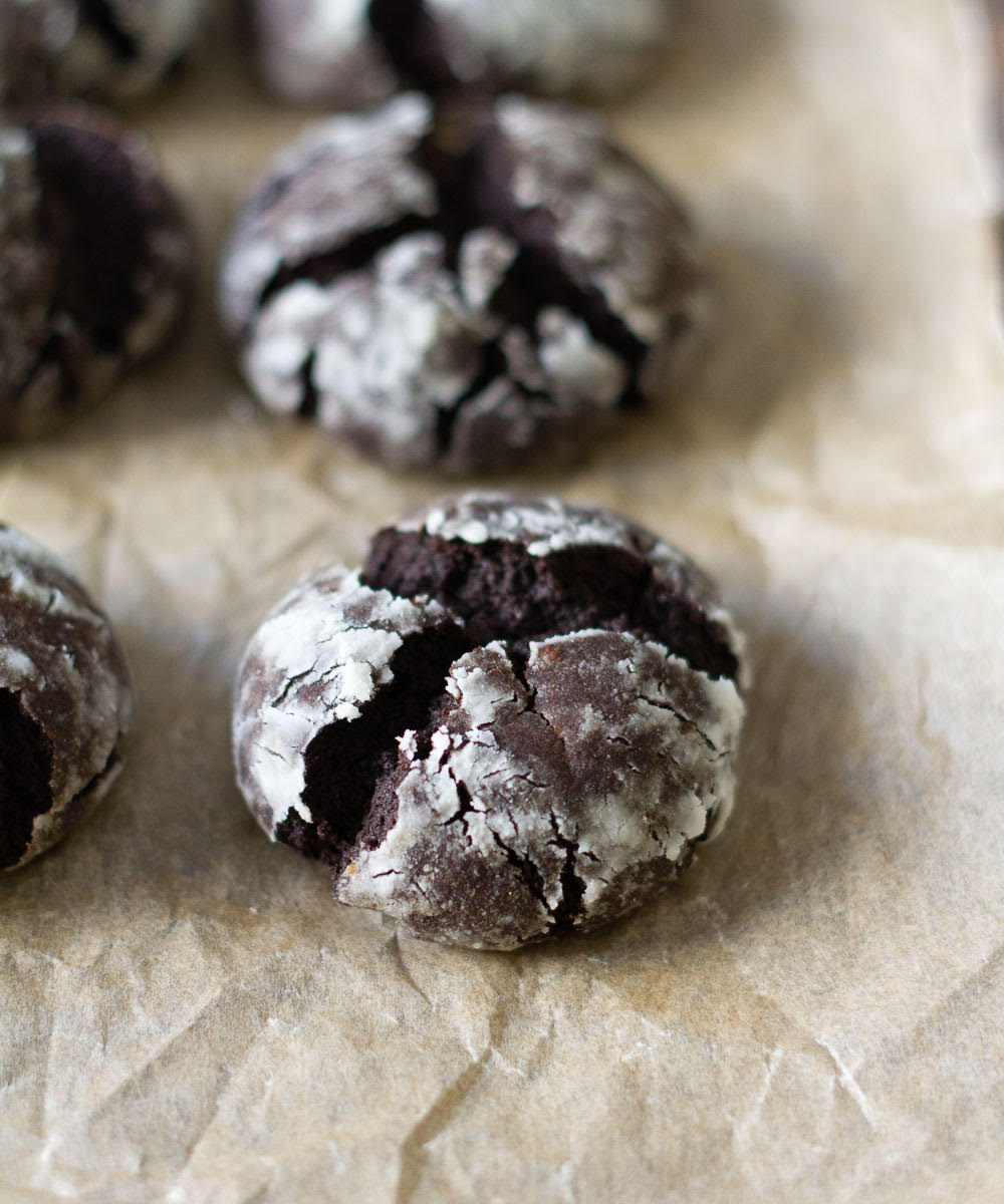 Baked chocolate crinkle cookies on parchment paper.