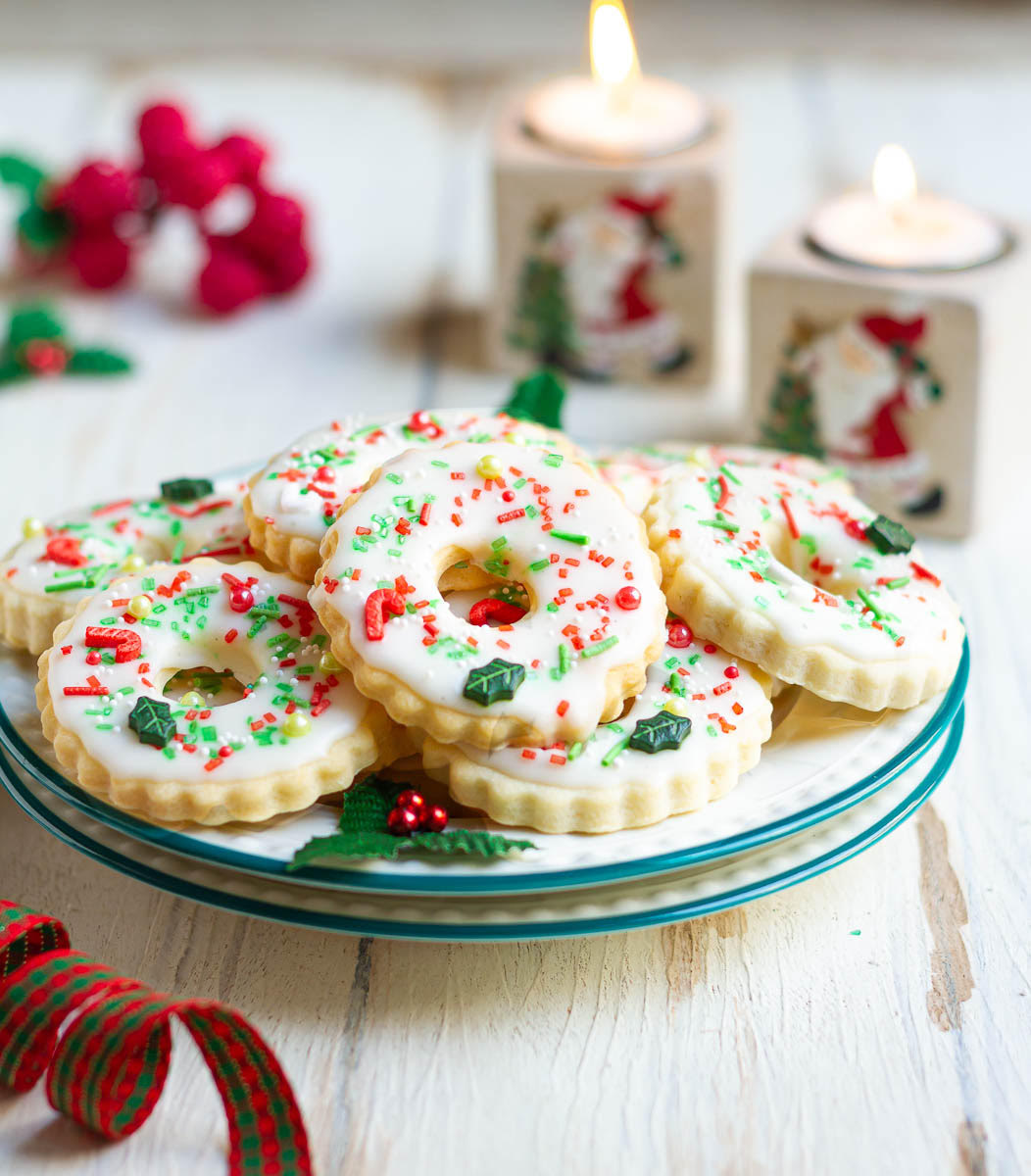 Christmas cookies with sprinkles and glaze on a plate.