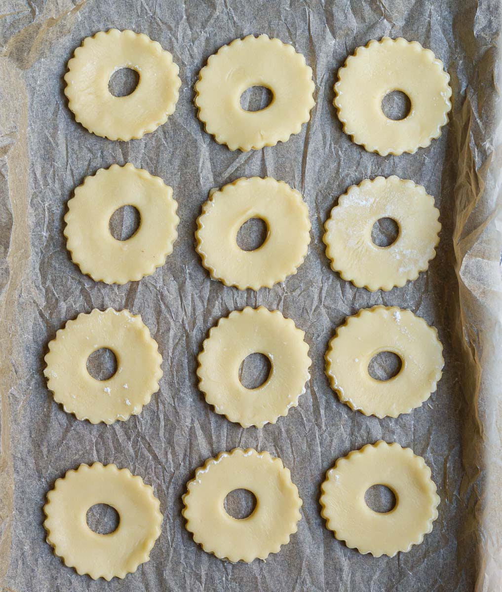 Wreath shaped cookie dough cut outs on a parchment-lined tray.