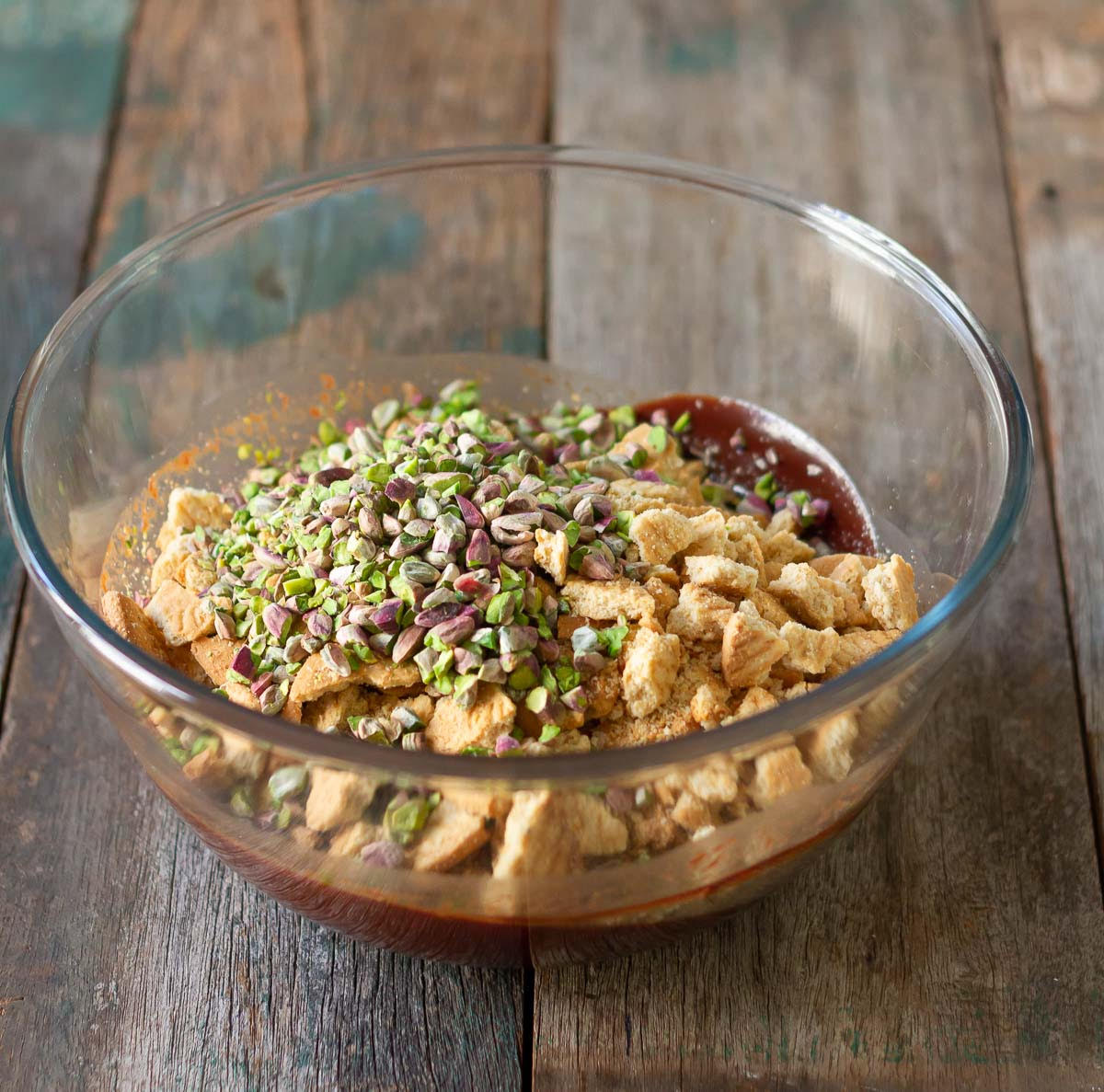 Crushed cookies and nuts on top of chocolate mixture in a mixing bowl.