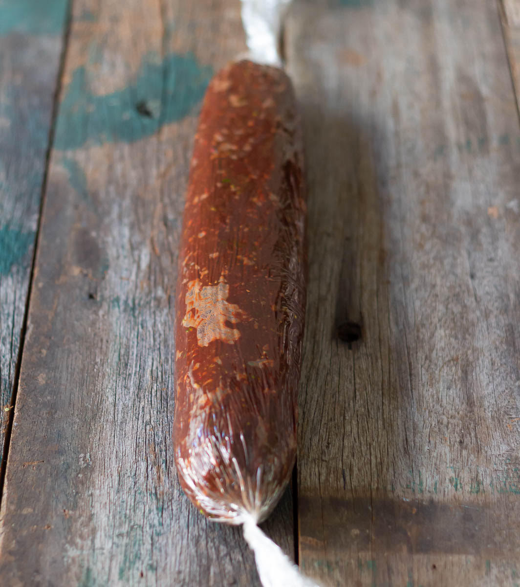 A log of chocolate biscuit mixture in a plastic wrap.