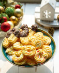 A platter of spritz cookies with Christmas decor around.
